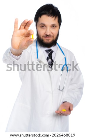 A doctor in a medical gown holds a yellow pill in front of him. focus on the pill. isolated white background