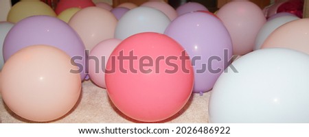 A lot inflated colored balloons on beige soft surface, texture for a festive background