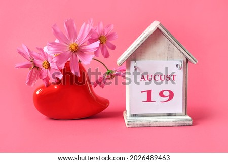 Calendar for: August 19 : the name of the month of August in English with the number 19 on the toy house, a bouquet of pink flowers in a heart-shaped vase, pink background