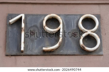 A sign on a wall with the number one hundred ninety-eight-198