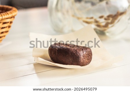 A little loaf of a rye bread, whole wheat bread on the 	cooking paper on a white wooden table