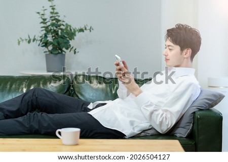 A man operating a smartphone while relaxing on the sofa