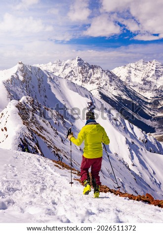 Man With Ski Poles Hiking In Deep Snow In Rocky Mountain Range