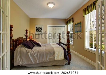 Beige bedroom with closet and carved wood bed with high poles