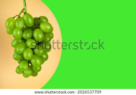 A bunch of grapes of white filling, on a yellow background, space for the text, on a green background