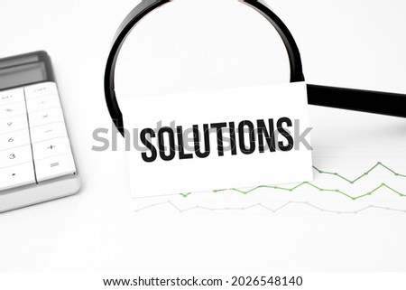 Business concept. Top view of calculator, magnifier, pen, table clock and notebook written solutions on wooden background.