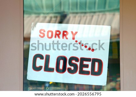 Close up on Sorry... Closed sign in glass window on brown wood door. Many businesses remain closed due to the Covid 19 pandemic and resurgence due to variant strains of the virus.