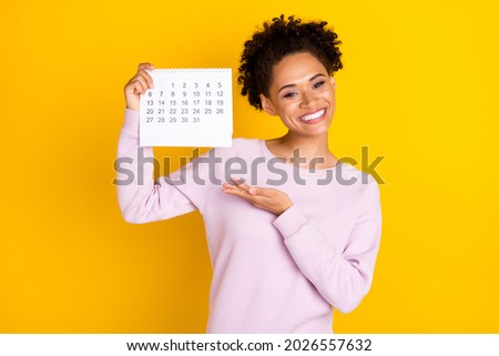 Photo of charming positive dark skin person hold demonstrate calendar isolated on yellow color background