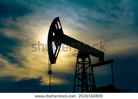 silhouette of a pumpjack with piston pump on an oil well against the background of sky