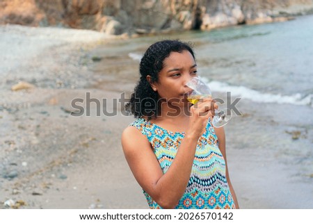 Woman enjoying a glass of wine by the sea.