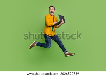 Full length profile side photo of mature man happy positive smile typing laptop jump isolated over green color background Royalty-Free Stock Photo #2026570739