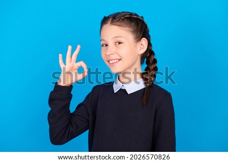 Photo of cheerful smiling good mood beautiful girl showing okay sign approval isolated on blue color background