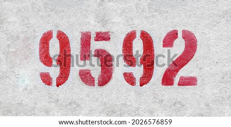Red Number 9592 on the white wall. Spray paint. Number nine thousand five hundred ninety two.