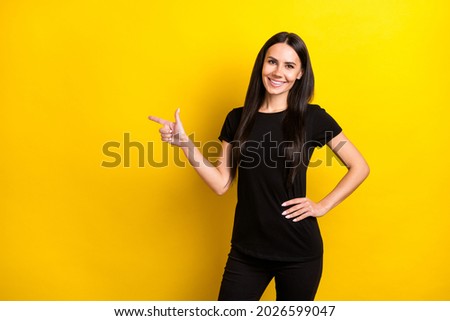 Portrait of charming girl put hand on waist indicate finger empty space offer isolated on yellow color background