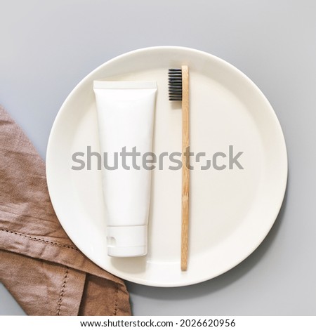 Ecology toothbrush on grey background. Brush on plate. Breakfast concept. Sustainable mouth product. Zero waste lifestyle. Organic accessory. Dental health at home. Biodegradable recycle. Toothpaste