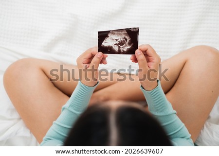 Asian pregnant woman looking to ultrasound image, focus on ultrasound image