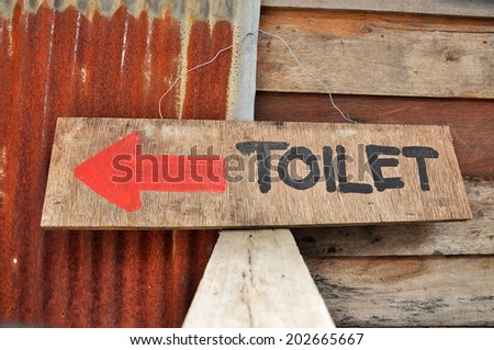 Signs to the toilets, which was written on a sheet of plywood.