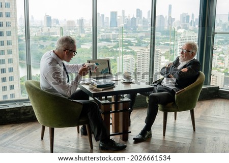 two senior management businessman debating  in meeting with data information in laptop. old man ceo discussing with client in cafe. serious mature manager talking by window over cityscape hi class  Royalty-Free Stock Photo #2026661534