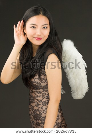 Asian young woman dressed up as an angel trying to listen carefully
