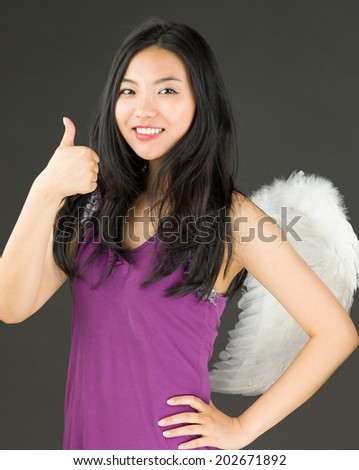 Angel side of a young Asian woman showing thumbs up sign and smiling