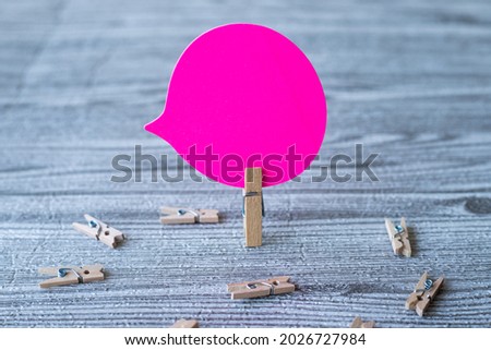 Piece Of Blank Speech Bubble Surrounded By Laundry Clips Showing New Meaning. Empty Conversation Balloon Clipped Upright Placed On Top Of Wooden Table Displaying Fresh Idea.