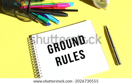 Notepad with text GROUND RULES with stationery. Yellow background color. Business concept.