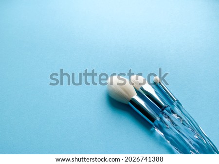 Brushes a flat lay with copy space. Beauty cosmetic makeup product layout. Stylish design. Creative fashionable concept. Cosmetics make-up brushes collection on a blue background, top view.
