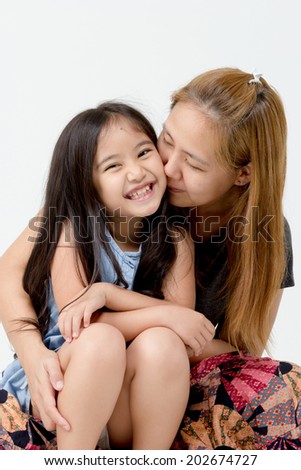 Portrait of happy Asian daughter kissed by mother