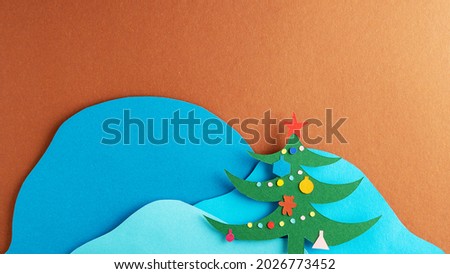 Christmas tree with decorations on the background of snowy mountains. Paper art.