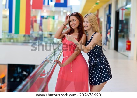two attractive woman friends talking and hanging out in shopping mall