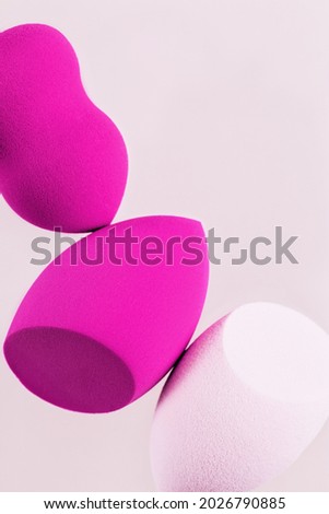 Cosmetic beauty blender sponges on light background with copy space. Purple and pink colored sponges different shape close up with soft texture. View from above.