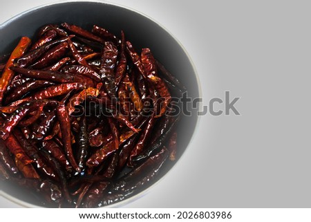 Grilled fresh spicy red chilli peppers in hot pan isolated on grey background, dark tone color.