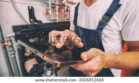 The technician checking the heating system in the boiler room with tablet in hand Royalty-Free Stock Photo #2026812668
