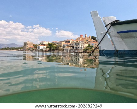 Underwater split photo of small port of Hirolakas in picturesque fishing village of Galaxidi with beautiful neoclassic houses and marine history, Fokida, Greece