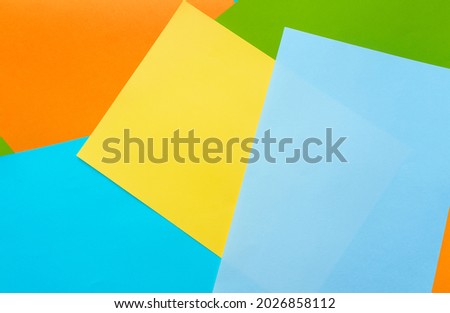A five sheets of colored paper (blue, turquoise, yellow, green, orange) are mixed. Design cardboard background, copy space.