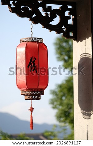 Closeup of a red Chinese lantern, a Chinese character pronounced "Qian" printed on it. It is a popular Chinese family name. English translation of the Chinese character: Money. 