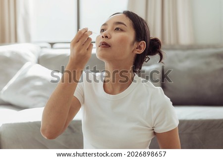 Young woman self test for COVID-19 at home with a nasal swab. asian woman using coronavirus covid-19 rapid antigen home testing kit, Coronavirus nasal swab test for infection. Royalty-Free Stock Photo #2026898657