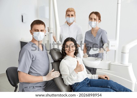 Team of professional dentists in uniform taking pictures and healing teeth of client during work in contemporary office of dental clinic