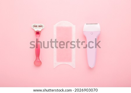 Razor, wax strip and electric epilator on light pink table background. Pastel color. Closeup. Female accessories for smooth body skin. Royalty-Free Stock Photo #2026903070