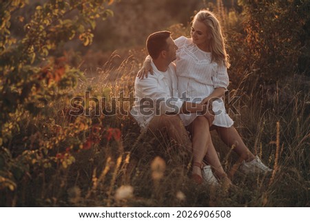 Pregnant woman and her husband hugging on the tummy together in nature outdoor