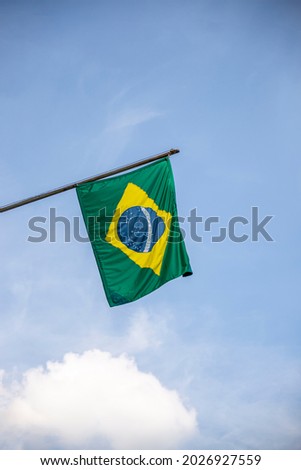 Brazil flag. Brazilian flag displaying on a pole in front of the house. National flag of Brazil waving on a home hanging from a pole on a front door of a building. Royalty-Free Stock Photo #2026927559