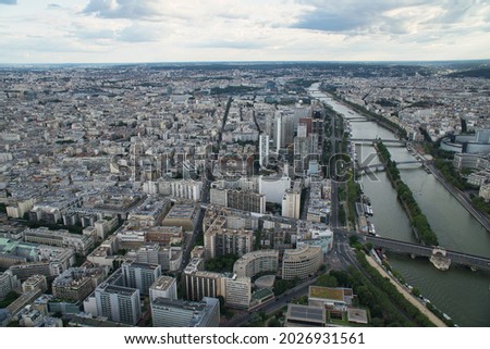 A panoramic aerial view of Paris skyline including river Seine lined with boats, a golden doom of Palace of invalides and other historical monuments, parks and gardens
