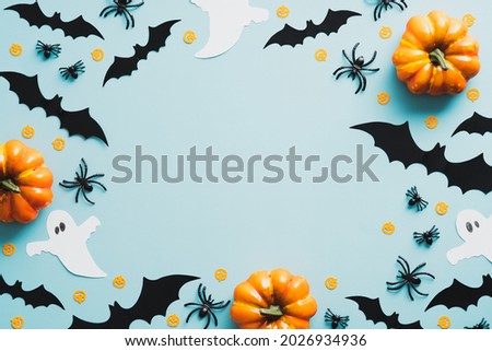 Happy Halloween holiday concept. Flat lay composition with pumpkins, bats, ghosts, spiders on blue background. Top view with copy space.