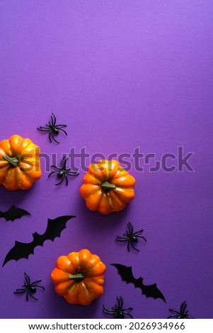Happy Halloween holiday concept. Halloween decorations, pumpkins, bats on purple background. Halloween party greeting card mockup with copy space. Flat lay, top view, overhead.