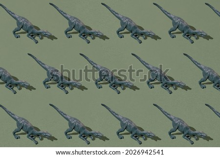 Arranged small gray dinosaur plastic toy on green background. Minimal design. Pattern.