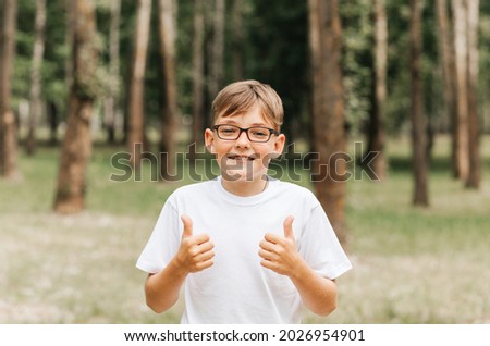 Funny boy with freckles and glasses shows a sign of class in nature. Positive children's emotion