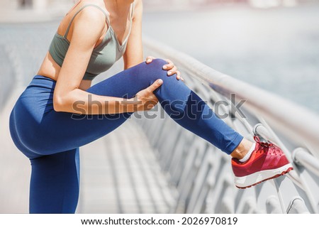 Young woman was running along the embankment and suddenly felt a sharp pain in the knee joint due to a dislocation or rupture of the meniscus Royalty-Free Stock Photo #2026970819