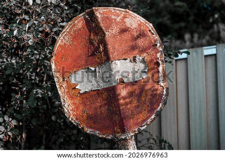 Rusty prohibition road sign. Stop symbol in bad condition. Old signpost with peeling paint. Post-apocalyptic picture