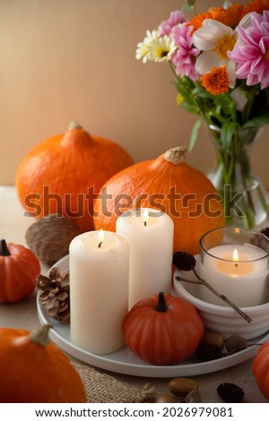 Autumn centrepiece, candles, autumn flowers and pumpkins on table
