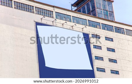 Blank billboard on the facade. Realistic sticky note isolated on facade. Advertising space on cement building wall with windows